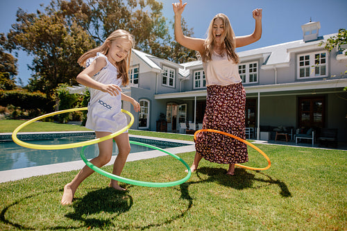 Mother and daughter playing with hula hoop in their backyard
