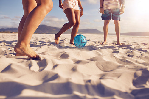 Friends playing soccer on the beach