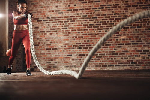 Tough woman exercising with battling rope