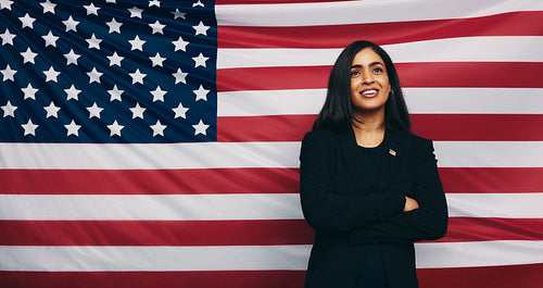 Thoughtful congresswoman smiling against an American flag