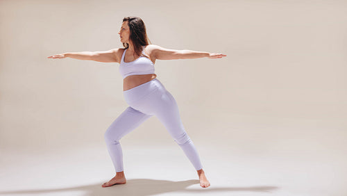 Warrior pose for pregnancy: Healthy and fit mom-to-be practicing prenatal yoga in a studio