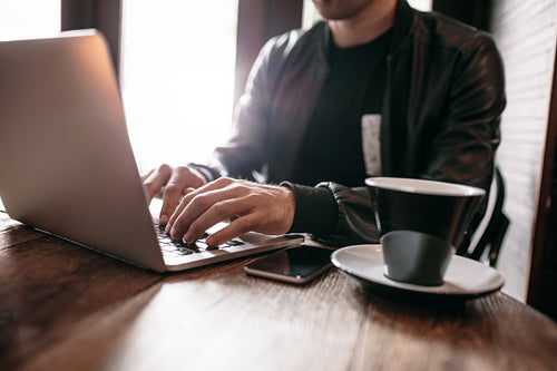 Young man at cafe working on laptop