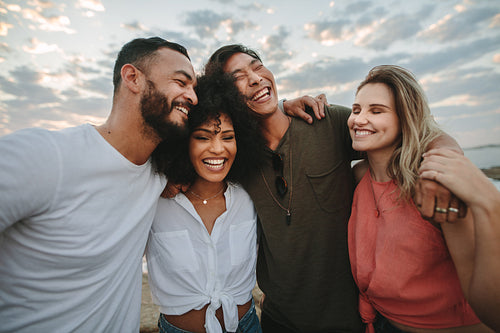 Group of friends standing together at the beach and laughing