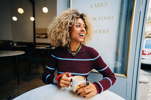 Woman smiling with coffee in a cozy cafe