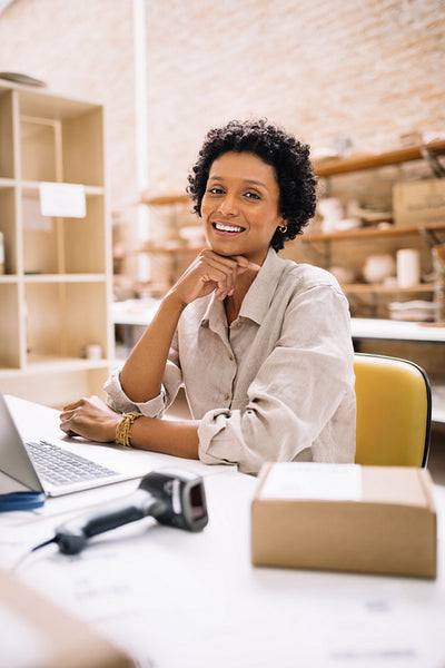 Cheerful young businesswoman smiling at the camera in a warehouse