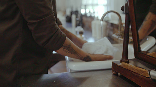 Barber soaking a towel in sink