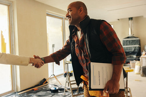 Professional contractor shakes hands with happy homeowner for interior renovation project