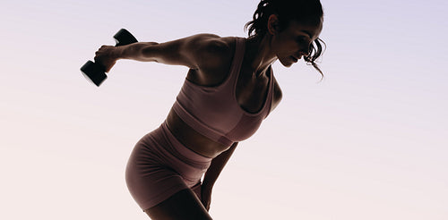Female athlete in fitness clothing demonstrating strength training with dumbbells