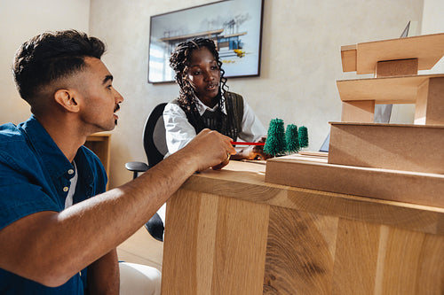 Young architects discussing a model structure in modern workspace