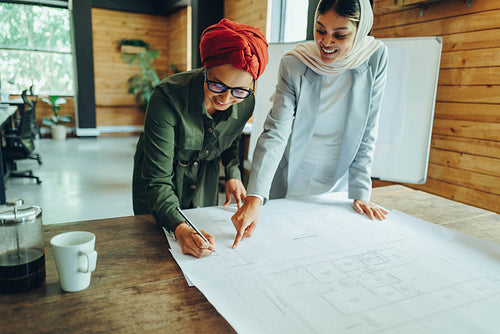 Cheerful Muslim architects working on blueprint drawings