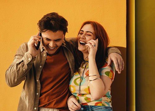 Happy friends laughing and talking on phones outside on a sunny day