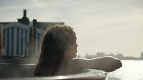 Woman relaxing in outdoor hot tub with steam and spa wellness view