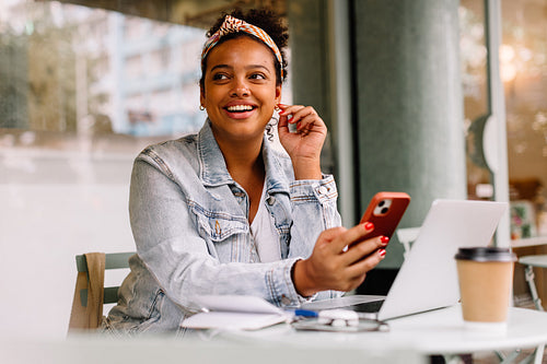 Happy college student enjoying a coffee break and using smartphone in a cafe