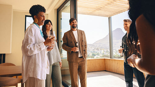 Group of friends enjoying drinks and laughter in a modern home on a sunny day