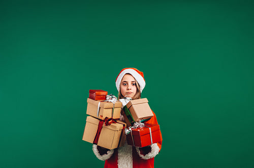 Girl in santa claus costume holding gift boxes