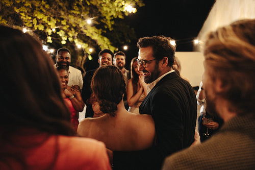 Guests celebrate under string lights at a cozy evening wedding gathering