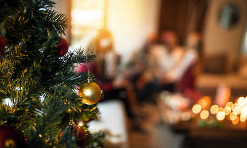 Decorated christmas tree at home with family sitting in background