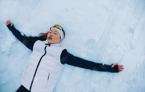 Female athlete resting in snow after workout in winter landscape