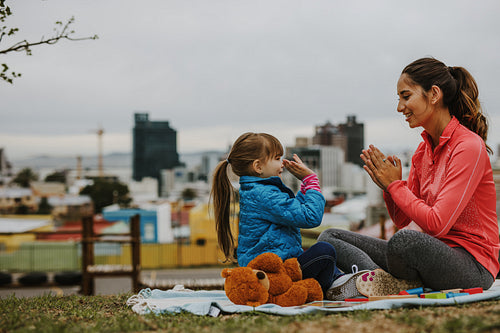 Girl playing patty-cake game with her nanny outdoors
