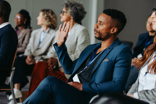 Businessman raising hand during conference presentation to ask a question