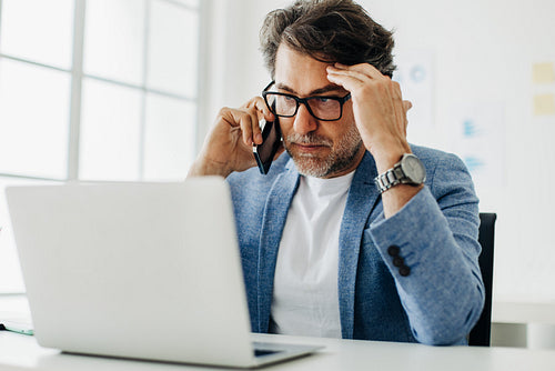 Frustrated business man having a phone call at his office desk