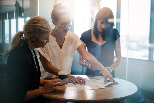 Female colleagues having a standing meeting around table