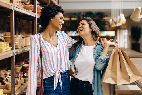 Two happy young women shopping in a ceramic store