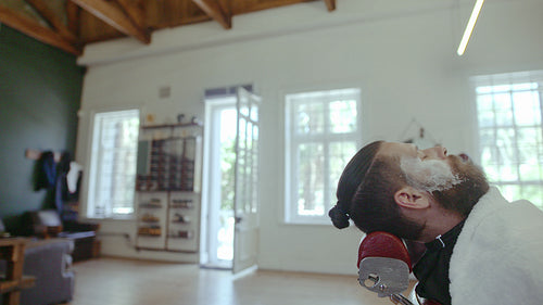 Professional barber shaving customer