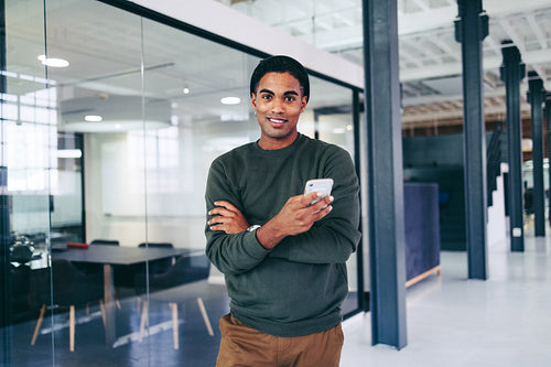 Creative young businessman holding a smartphone in a modern office