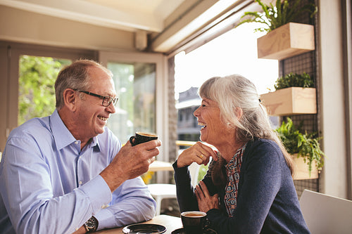 Cheerful senior couple talking over a cup of coffee at cafe