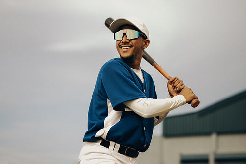 Smiling baseball player in blue jersey ready to play on a sunny day