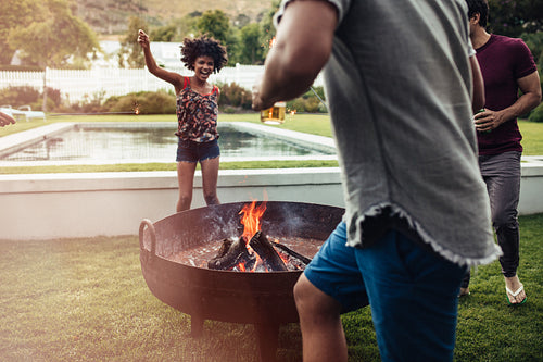 Group of friends dancing around campfire in backyard