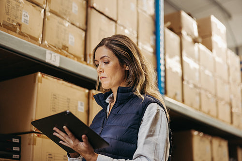 Female logistics worker doing stock control using a digital tablet