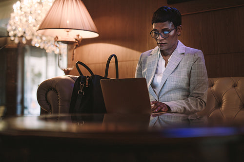 Female CEO on business trip using laptop in hotel lobby