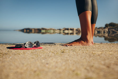Swim goggles on the sand with a woman standing by