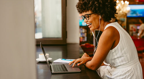 Smiling woman sitting at cafe using laptop