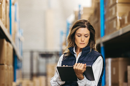 Warehouse worker looking at an inventory list on a digital tablet