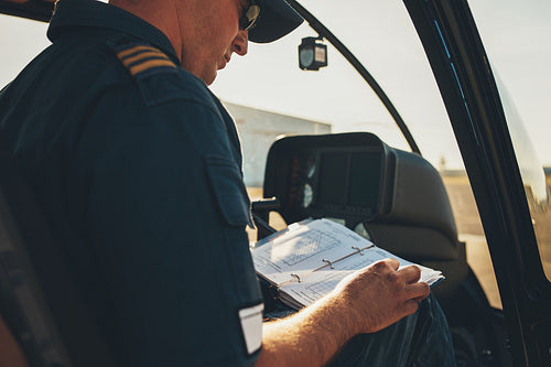 Man helicopter pilot reading a manual booklet