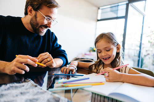 Father and daughter drawing together at table