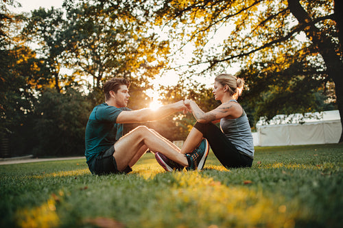 Young couple cooperating while stretching at park
