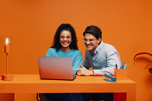 Happy colleagues brainstorming with a laptop in a smart casual office setting
