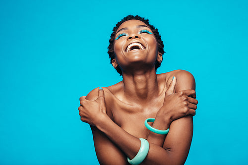African woman with vivid makeup hugging herself