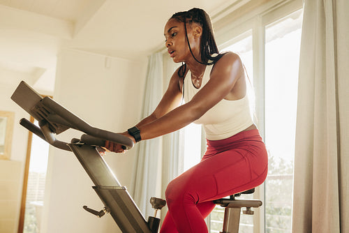 Healthy lifestyle goals: Young African woman works out with digital fitness bike