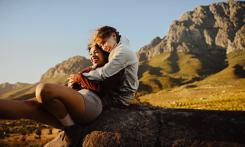 Couple embracing on scenic mountain rock