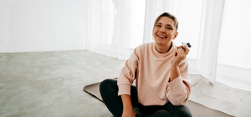 Relaxing post workout with woman enjoying snack on yoga mat