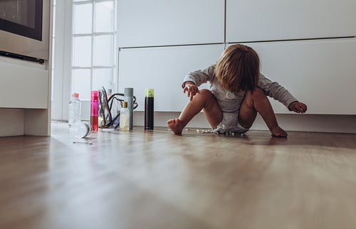 Kid sitting on floor at home playing with cosmetic bottles