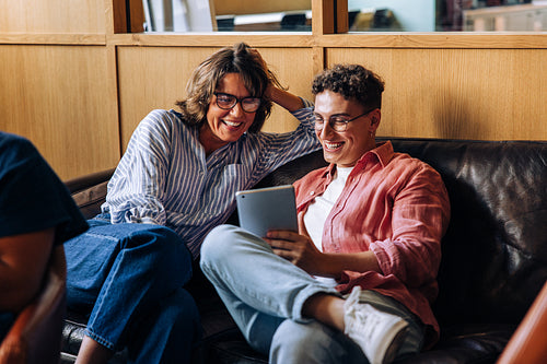 Middle-aged woman and young man enjoying tablet together on a sofa