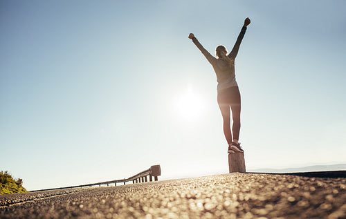 Low angle view of a woman standing on a stone pillar