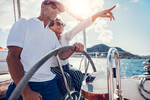 Happy senior couple at the wheel of a yacht
