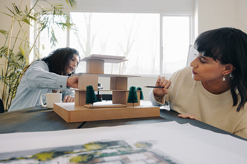 Project managers discussing architectural model in modern office setting